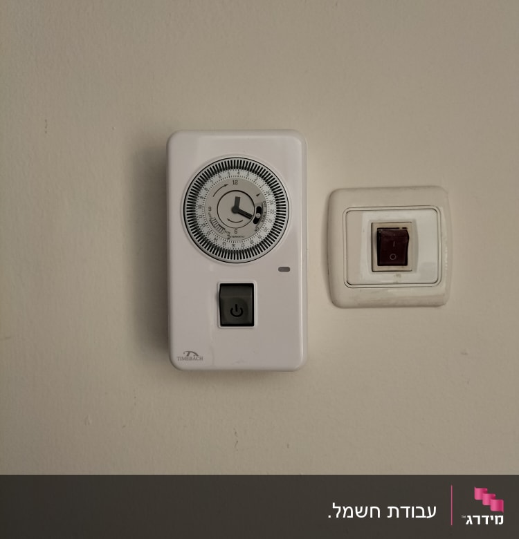 טיימר חשמלי ומתג על קיר לבן